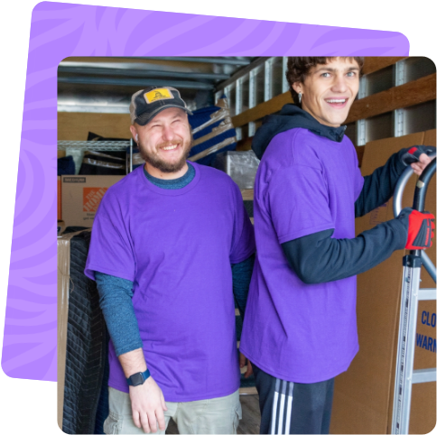 Two smiling Ventura movers with a hand truck by the moving truck